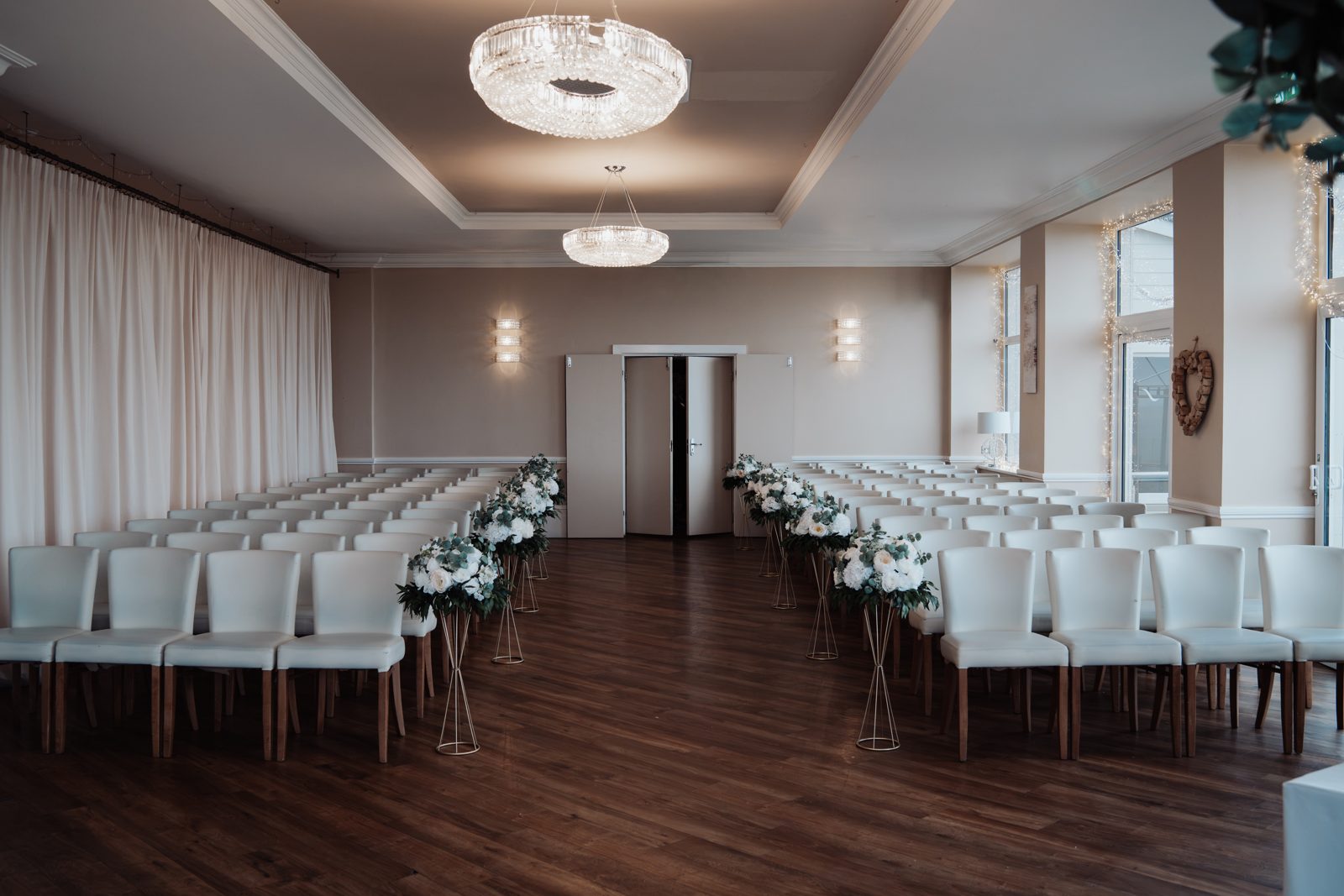 Ceremony aisle lined with ivory floral arrangements on gold stands