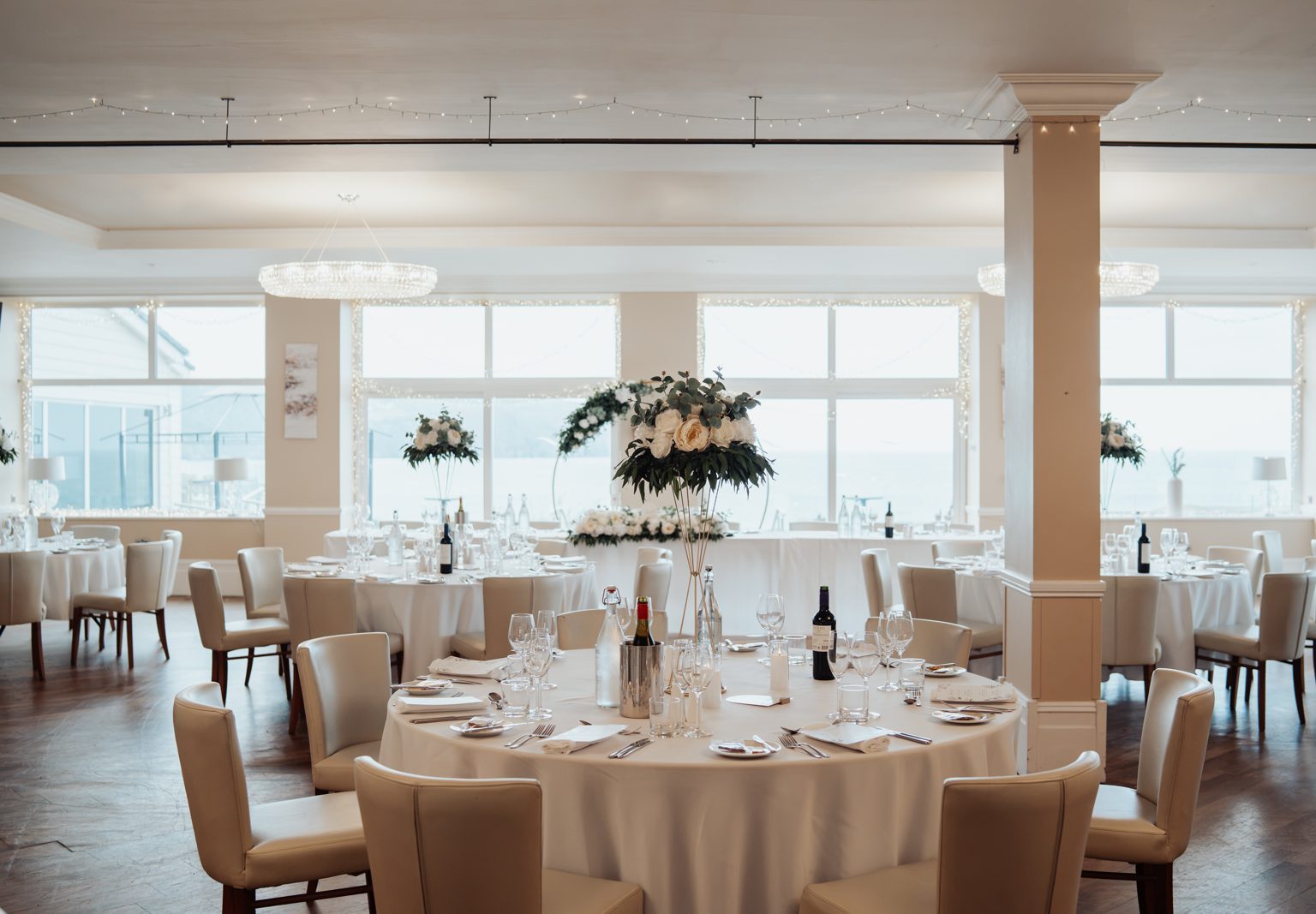 Wedding reception room with tall ivory floral arrangements on gold stands